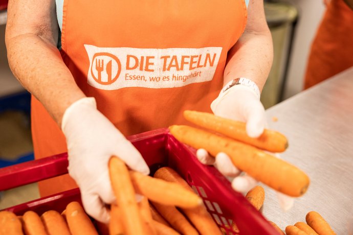 Helfer bei der Tettnanger Tafel mit Karotten in der Hand