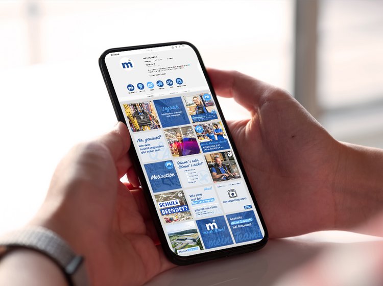 Instagram Feed – Handy-Mock-up Hand hält Smartphone mit geöffnetem Instagram-Feed, auf dem verschiedene Unternehmensbeiträge sichtbar sind.