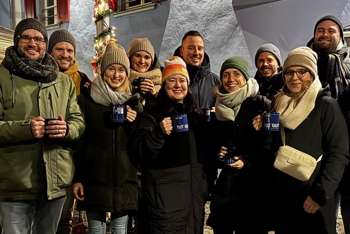 Gruppe von Menschen bei einer festlichen Veranstaltung im Freien, mit rotem Schirm und Lichterdekoration.