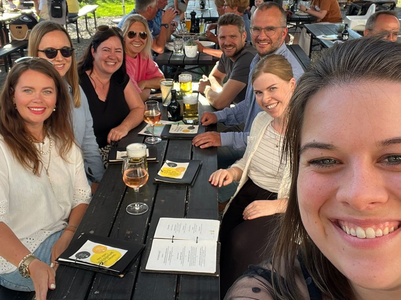 After-Work mit guter Laune Team lächelt in die Kamera bei einem sommerlichen Afterwork