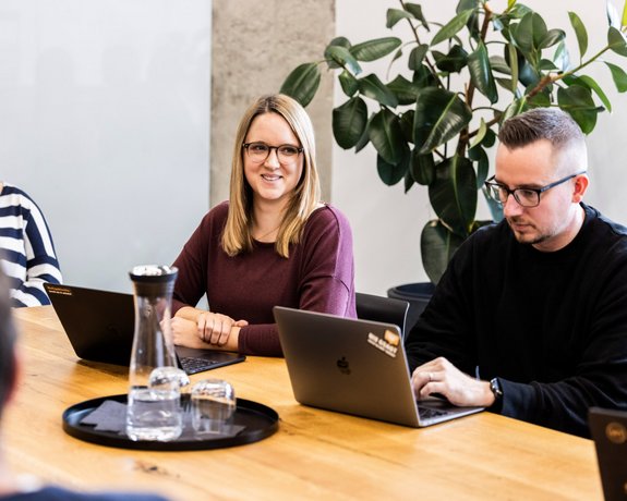 Kreativrunde im Büro Vier Alpenblickdrei-Teammitglieder in angeregter Diskussion am Konferenztisch.