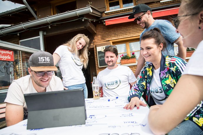 AB3 Kollegen im Ausflugslokal in den Alpen vor dem Tablet beim Brainstorming