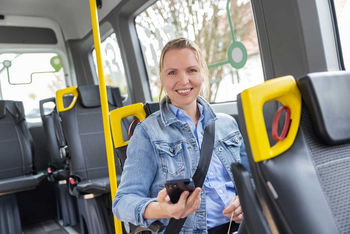 Person sitzt angeschnallt mit Handy im MOBI