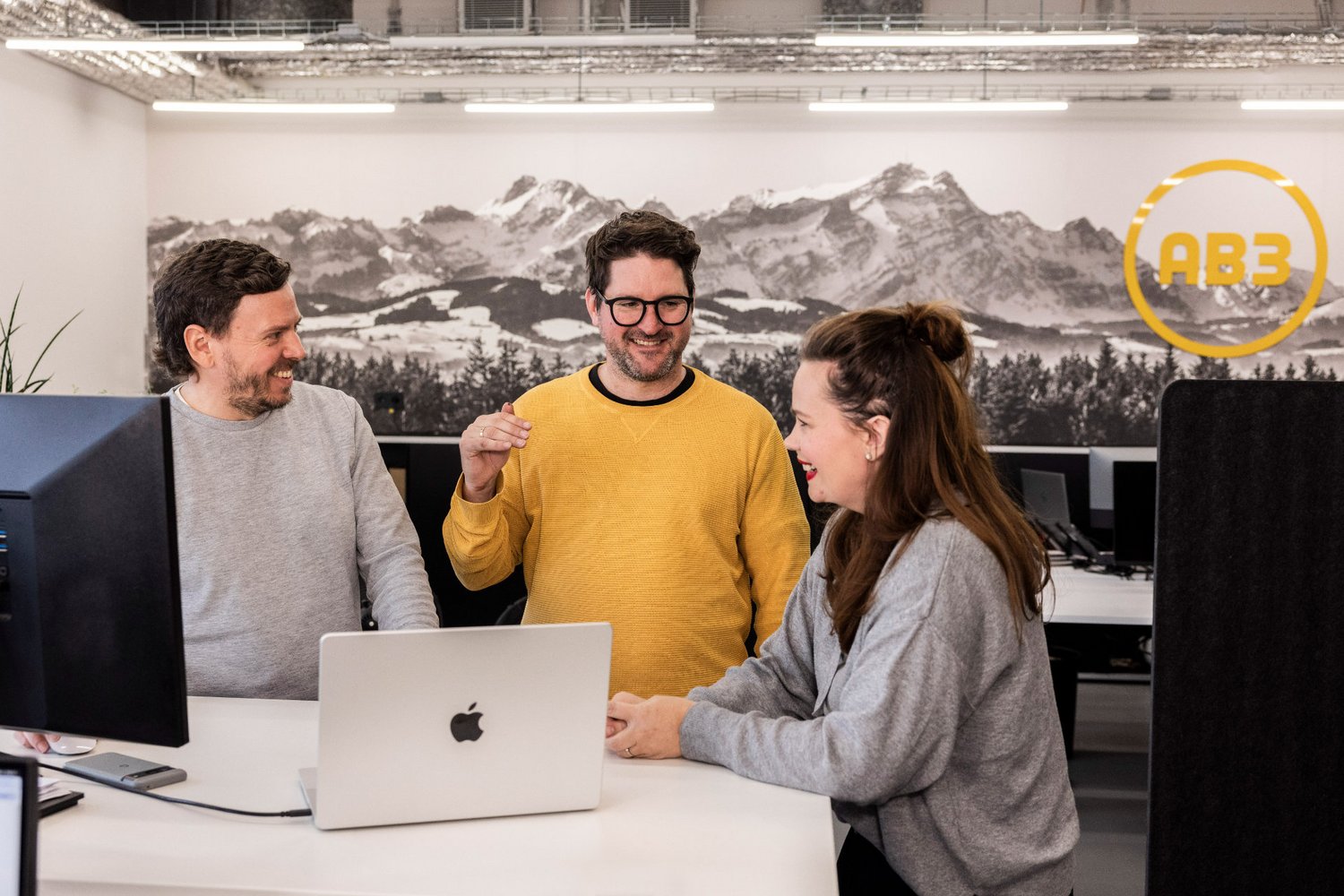 Drei Personen unterhalten sich entspannt in der offenen Küche der Alpenblickdrei Werbeagentur.