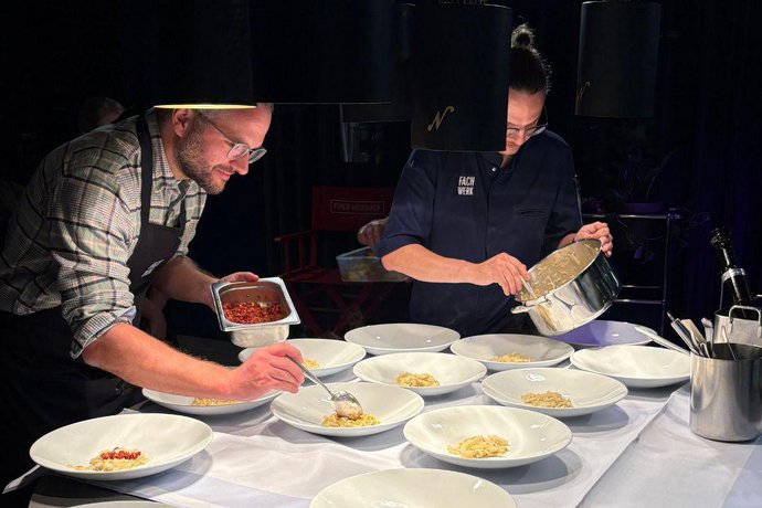 Personen bereiten in einer Küche gemeinsam Speisen zu.