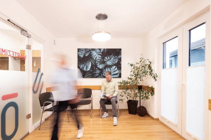 Personen im Wartezimmer der Hausarztpraxis Dr. Schön & Kollegen