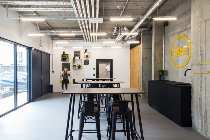 Frau auf Schaukel in Werbeagentur Tettnang mit Stehtischen, Stühlen und Küche