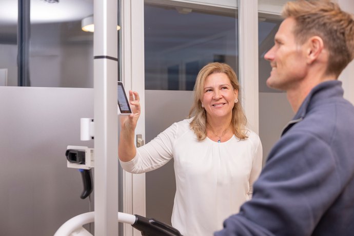 Doren Alfeldmisst mit einem Gerät die Körperwerte eines Mannes, der auf einem Fahrrad-Ergometer trainiert.