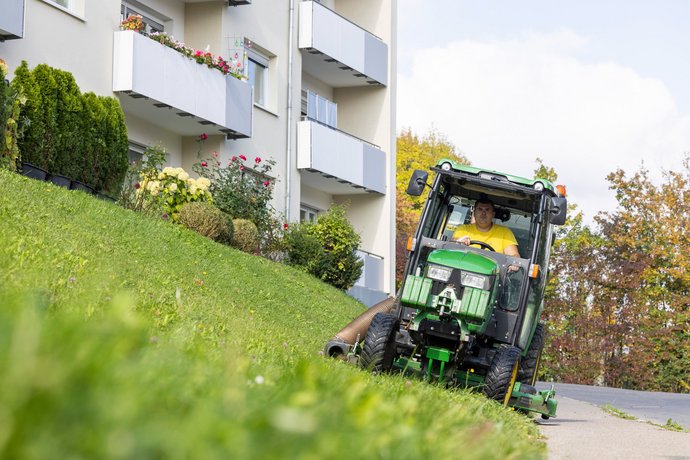 Mann mäht Rasen vor einem modernen Mehrfamilienhaus der SWG.