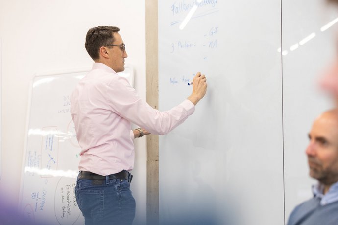 Armin Hipper schreibt Armin Hipper schreibt etwas auf ein Whiteboard.