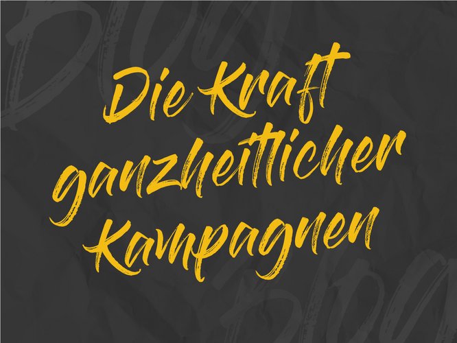 Gelbe handgeschriebene Schrift auf dunklem Hintergrund mit der Botschaft „Die Kraft ganzheitlicher Kampagnen“