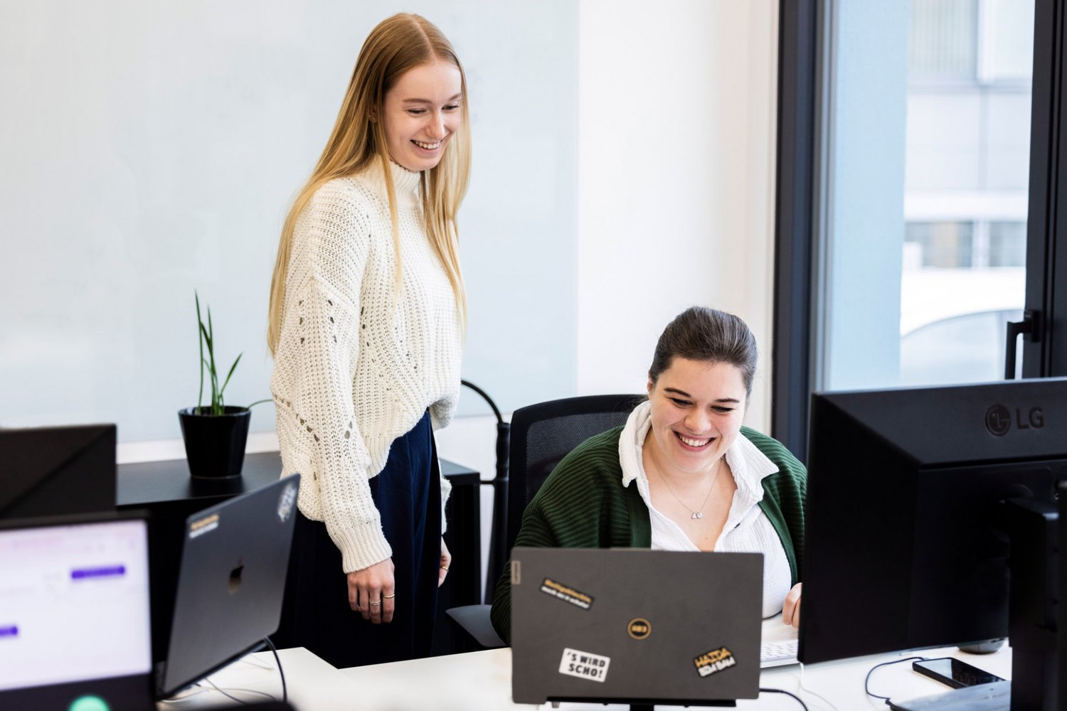 Zwei Kolleginnen arbeiten am Schreibtisch bei Alpenblickdrei