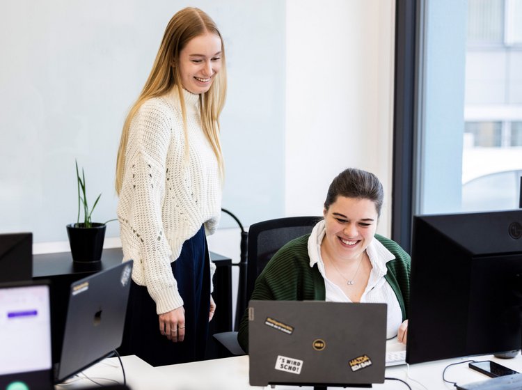 Kolleginnen bei Alpenblickdrei Zwei Kolleginnen arbeiten am Schreibtisch bei Alpenblickdrei