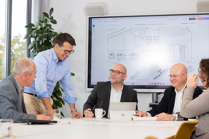 Meeting mit mehreren Personen an einem Konferenztisch, moderne Büroatmosphäre.