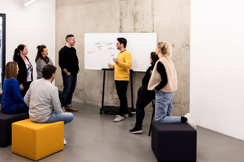 Teammitglied der Alpenblickdrei Werbeagentur schreibt Notizen an ein Whiteboard während eines Workshops.